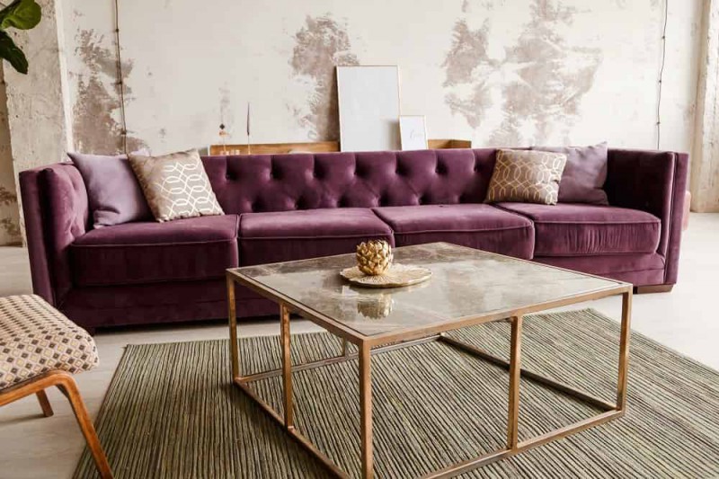 Salon z fioletową sofą i ozdobnymi poduszkami